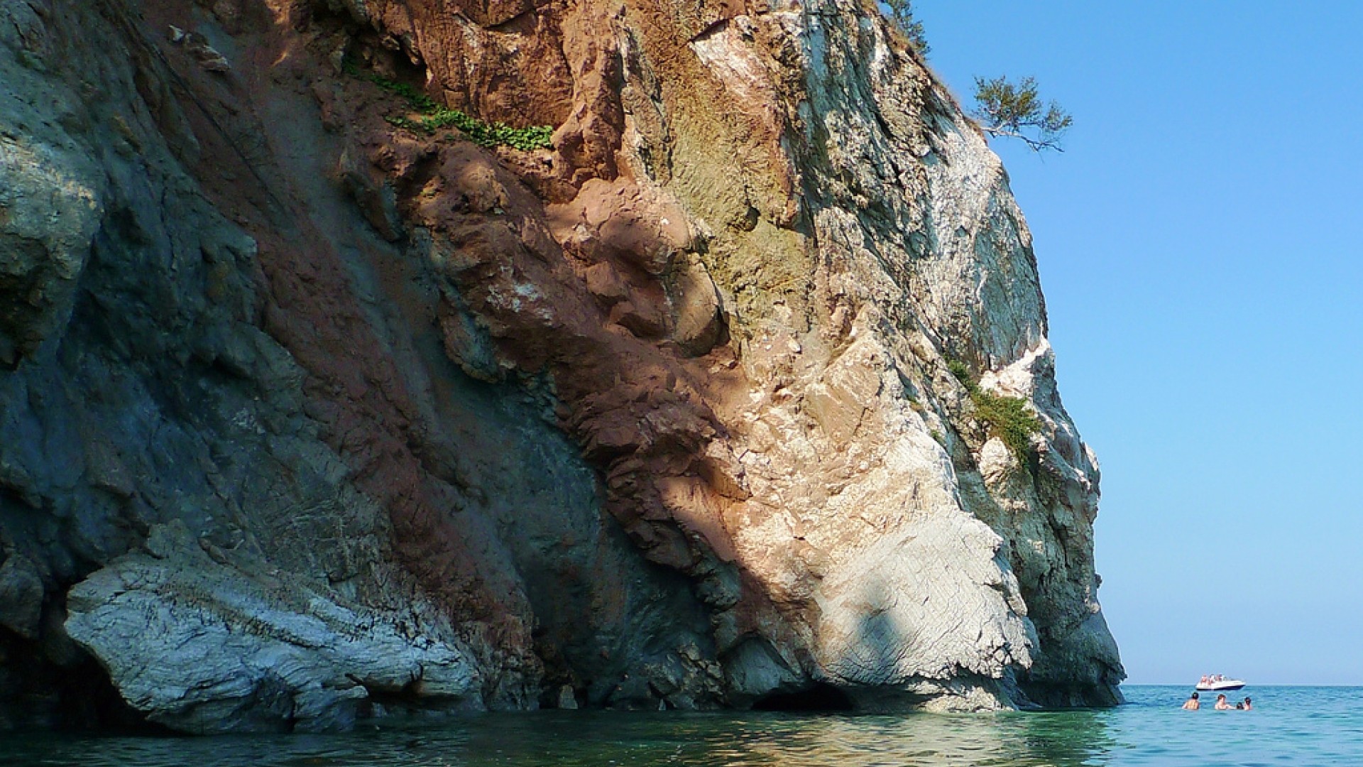 Oceanside cliff and people swimming in the water