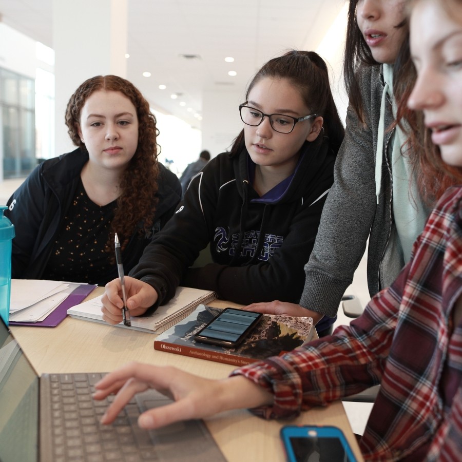 Close up of students studying at a table on the second floor of Mulroney Hall.