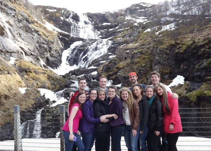 A group of people standing in front of a waterfall&quot;