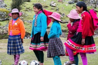Peruvian children playing soccer in traditional clothes