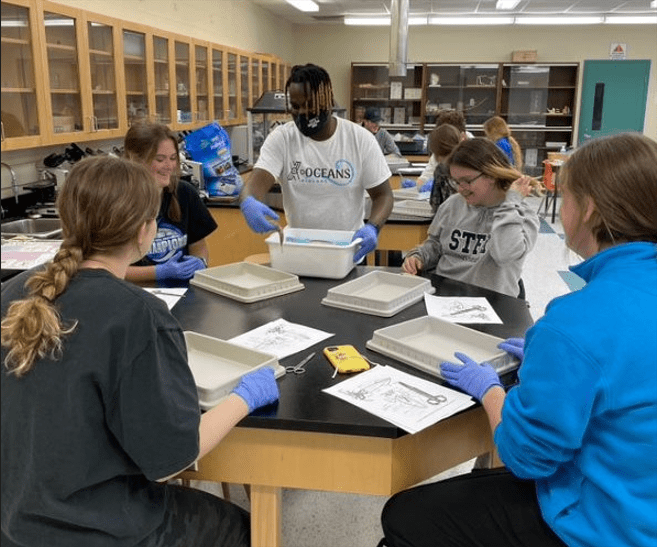 Student Leader Instructing School Students on Squid Dissection