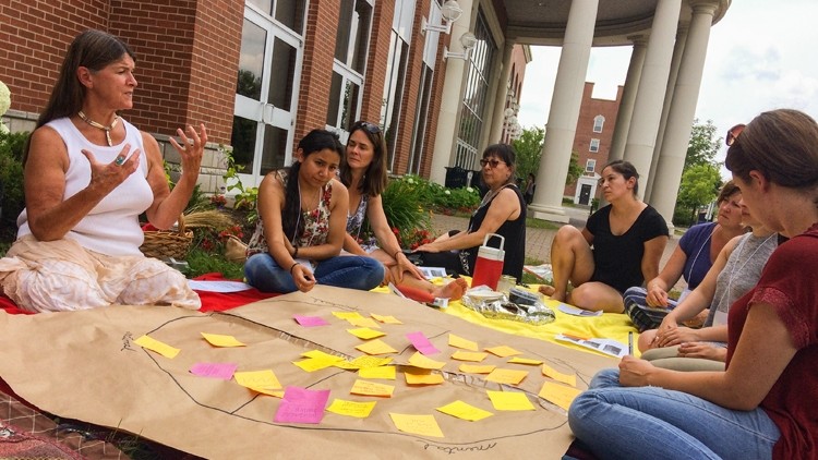Students Sit Together in Circle While a they Receive Mentorship from a Fellow Student