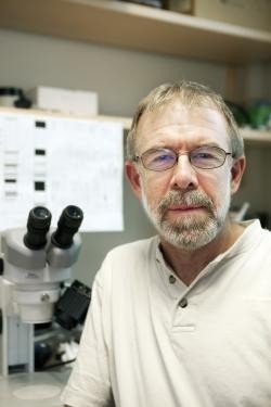 Person in glasses with microscope in background