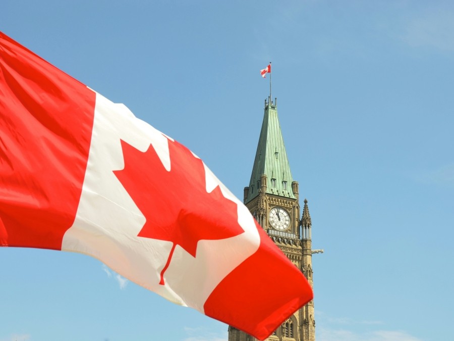 Canadian flag with the Peace Tower behind it.