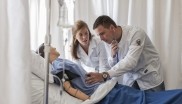 Two people in white coats working on a simulated patient in a nursing education setting