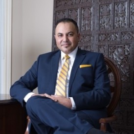 Dark skinned smiling middle-aged man sitting on a chair